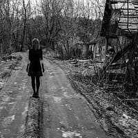 A black and white picture showing a girl walking in the middle of the road