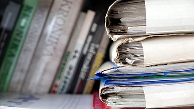 A pile of different documentation stacked in front of books